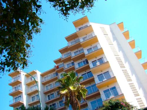 a tall building with a palm tree in front of it at Hotel Vista Odin in Playa de Palma