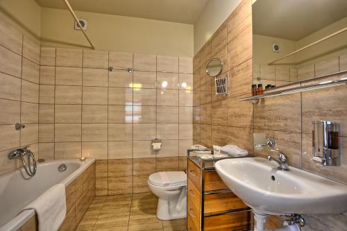 a bathroom with a tub and a sink and a toilet at Pensjonat Szajna Spa in Rymanów-Zdrój