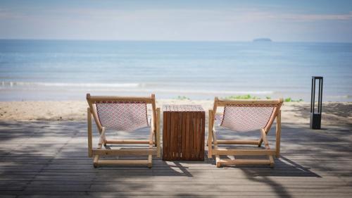 two chairs and a table on the beach at The Ryad Rayong in Mae Pim