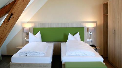 a bedroom with two beds and a green headboard at Hotel Rössle in Fürstenberg