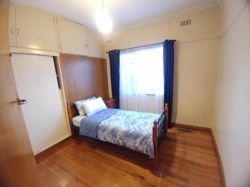 Habitación pequeña con cama y ventana en Ideal Business and Family accommodation, en Dandenong