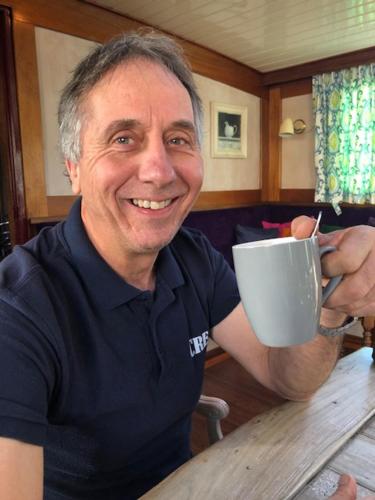 a man sitting at a table holding a coffee cup at Botel Elodie in Amsterdam