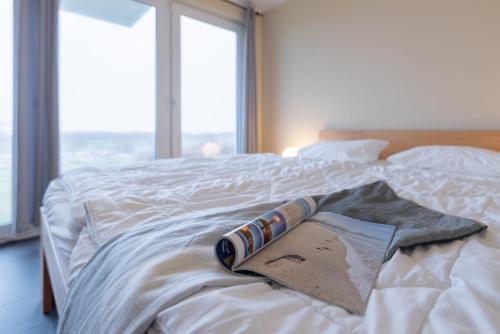 a book laying on top of a bed with a window at Haus Calmsailing in Börgerende-Rethwisch
