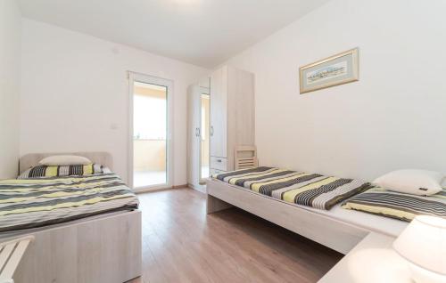 Habitación con 2 camas, paredes blancas y suelo de madera. en Apartman Dora, en Povljana