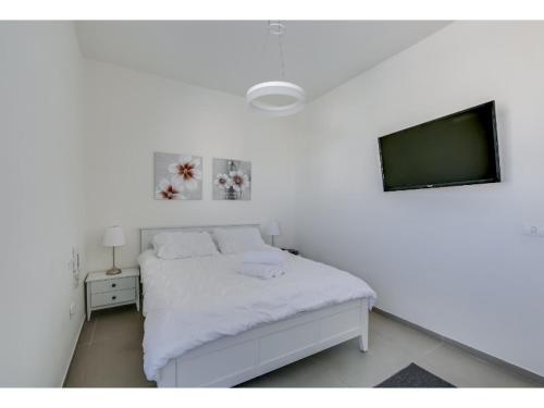 Un dormitorio blanco con una cama blanca y un televisor. en Luxury 2Bedroom brand new apt Carlton Hotel, en Tel Aviv