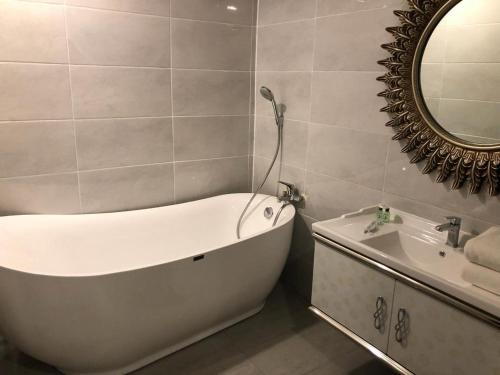 a bathroom with a tub and a sink and a mirror at The Apartments at Times Square Kuala Lumpur KL in Kuala Lumpur