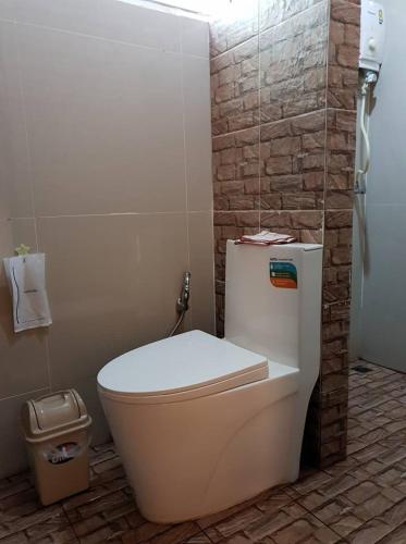 a bathroom with a white toilet and a brick wall at ร่มไม้สายธาร(Rommaisaitharn Resort) in Phrae