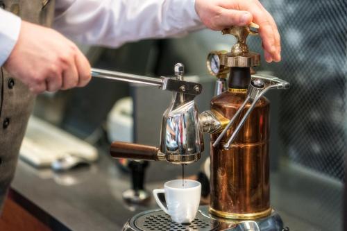 a person is pouring coffee into a coffee machine at Hotel HP Park Poznań Malta in Poznań