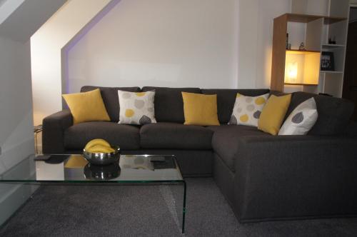 a living room with a gray couch with yellow pillows at No 7 Woods View in Bournemouth