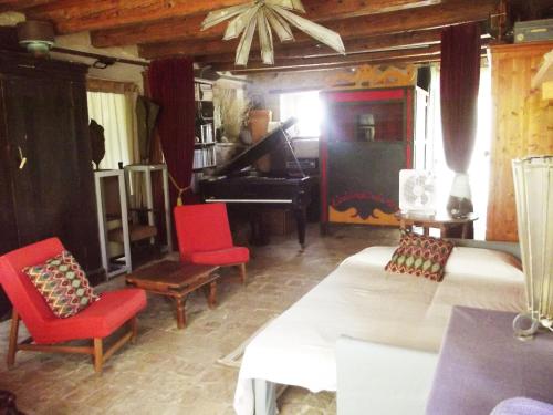 a living room with two beds and a piano at "La Casa degli ulivi Art B&B" in Trecastelli