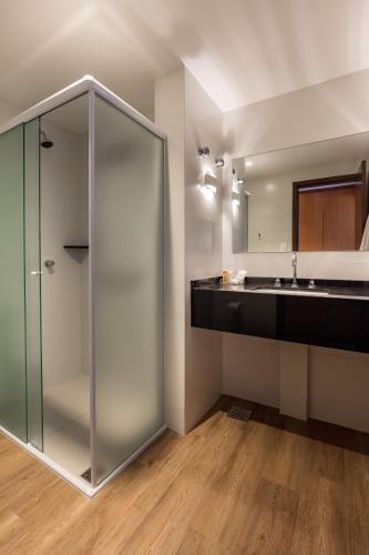 a bathroom with a glass shower and a sink at Monthez Hotel & Eventos in Brusque