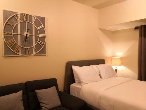 ein Schlafzimmer mit einem Bett und einer Uhr an der Wand in der Unterkunft Centrio Tower Beside Ayala Studio Unit -24 in Cagayan de Oro
