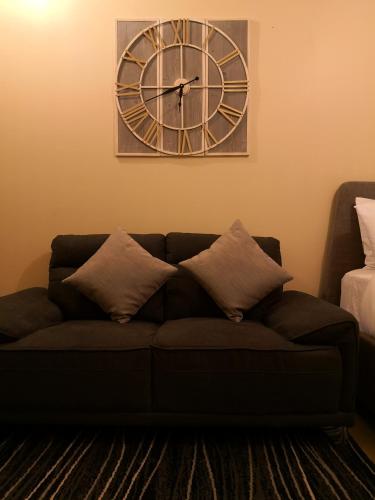 eine Uhr an der Wand über einer Couch mit Kissen in der Unterkunft Centrio Tower Beside Ayala Studio Unit -24 in Cagayan de Oro