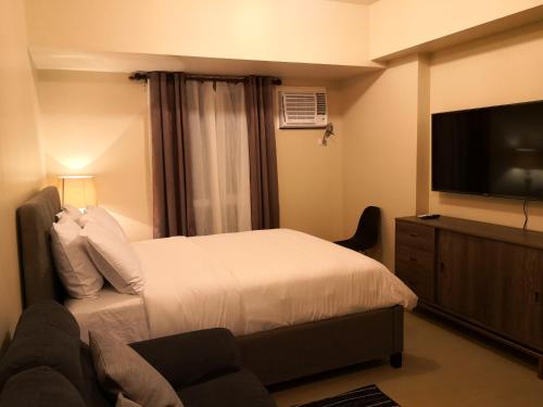 ein Hotelzimmer mit einem Bett und einem Flachbild-TV in der Unterkunft Centrio Tower Beside Ayala Studio Unit -24 in Cagayan de Oro