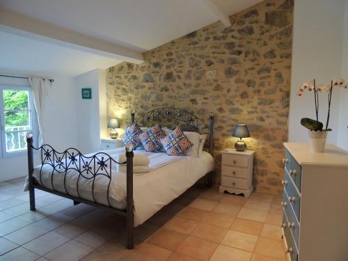 a bedroom with a bed and a stone wall at Maison Étoile in Néffiès