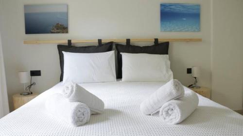 Un dormitorio con una cama blanca con toallas. en AZZURO, en Kavala