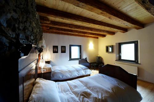 um quarto com 2 camas num quarto com tectos em madeira em Albergo Diffuso Comeglians em Comeglians