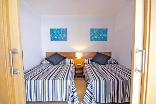 two beds in a small room with a hallway at Zeus Alexis Plus in Salou