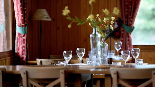 una mesa con vasos y un jarrón con flores. en Camping Cadí Vacances & Spa, en Gósol