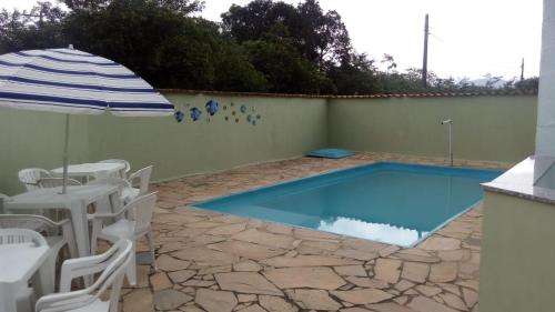 a swimming pool with an umbrella and a table and chairs at Chale Cantinho Albamar in Ubatuba