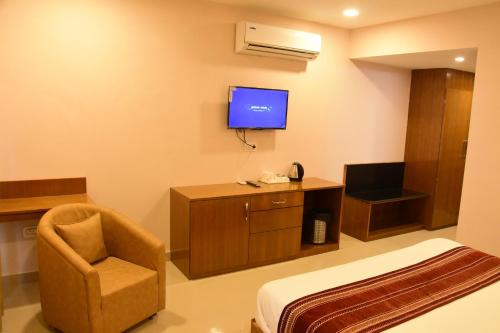 a hotel room with a bed and a chair and a tv at Rama Trident, Katra in Katra