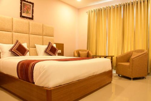 a bedroom with a large bed and two chairs at Rama Trident, Katra in Katra