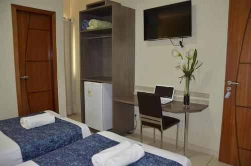 um quarto de hotel com 2 camas e uma mesa com um computador portátil em Palace Hotel em Altamira