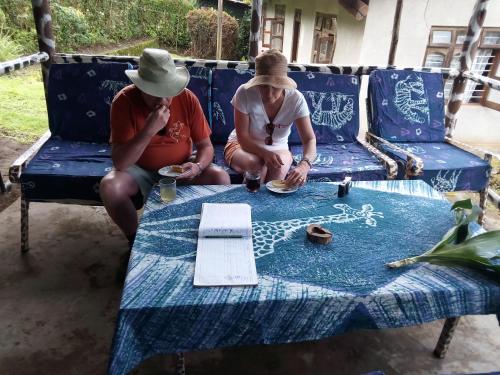 two people sitting on a blue bench with a table at Machame Nkweshoo Cultural Tourism in Machame