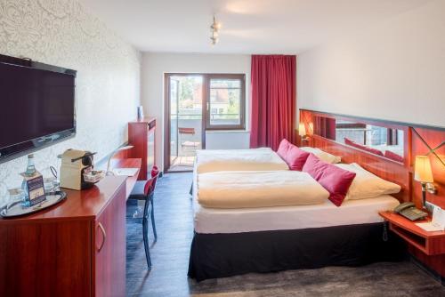 ヴュルツブルクにあるポスト ホテル ヴュルツブルクのベッド2台、薄型テレビが備わるホテルルームです。