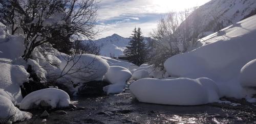 a stream covered in snow next to a mountain at Gasthof Pension Santeler in Sankt Leonhard im Pitztal