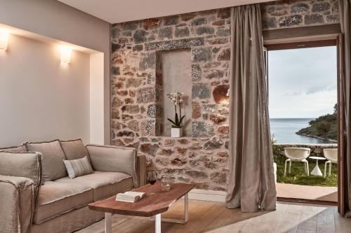 a living room with a couch and a stone wall at 100 Rizes Seaside Resort- Small Luxury Hotels of the World in Gythio