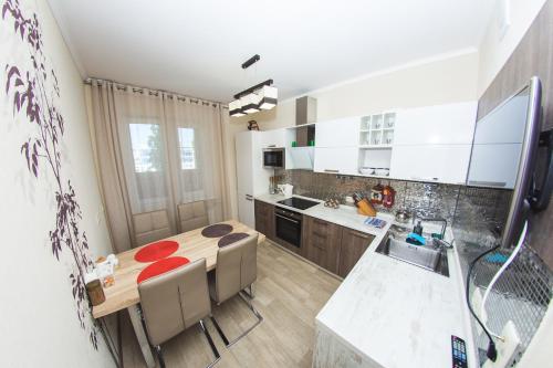 a kitchen with a wooden table and a kitchen with white cabinets at ATLANT Apartments 99 in Voronezh