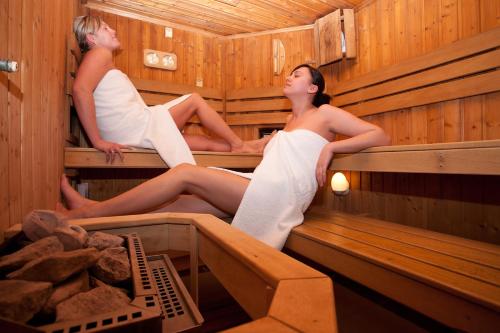 a man and woman sitting in a sauna at JANTAR-SPA Kompleks Wypoczynkowo-Rehabilitacyjny in Niechorze