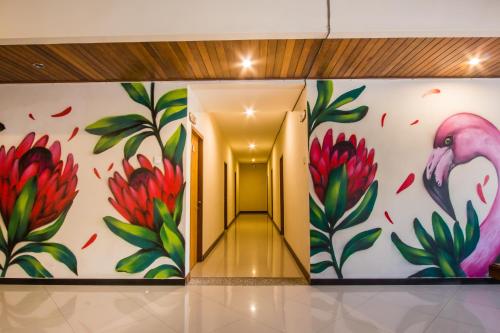 a hallway with a painting of flowers and a pink flamingo at Kuta Suci Guesthouse in Kuta