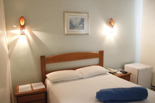 a bedroom with a bed with two lights on the wall at Pousada Sossego da Pampulha in Belo Horizonte