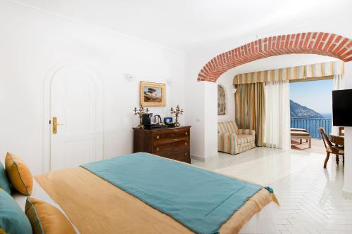 a bedroom with a bed and a couch and a chair at Hotel Le Agavi in Positano