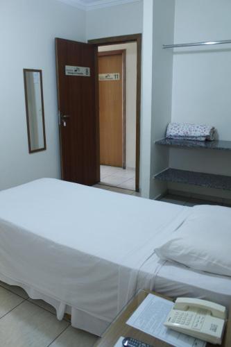 a bedroom with a bed with a phone on a table at Pousada Sossego da Pampulha in Belo Horizonte