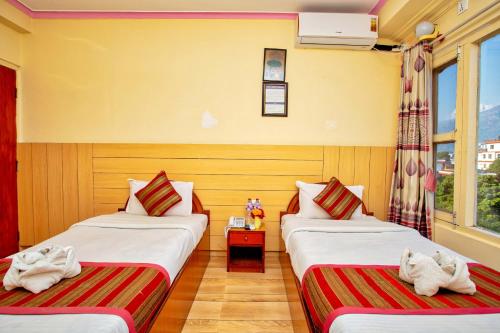 two beds sitting next to each other in a room at Hotel Grand Holiday in Pokhara