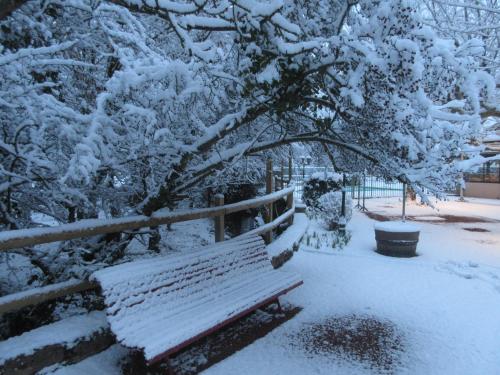 a park bench covered in snow next to a fence at Hôtel Restaurant Le Moulin de Saint Verand in Saint-Vérand