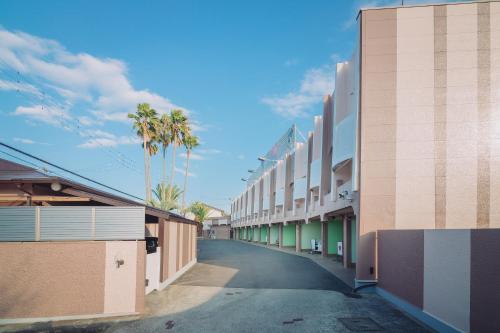 an empty street with palm trees and buildings at Tinkerbell (Adult Only) in Takamatsu