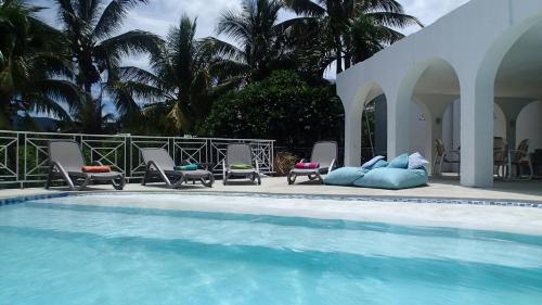 a swimming pool with chaises and chairs next to a house at Villa Talassa in Le Morne
