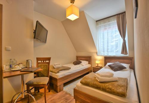 Habitación de hotel con 2 camas, escritorio y TV. en Pensjonat Szajna Spa, en Rymanów-Zdrój