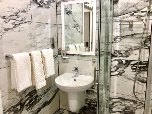 a bathroom with a sink and a shower at Ilford Hotel Goodmayes in Ilford