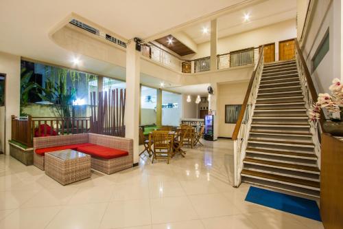 a living room with stairs and a table and chairs at Kuta Suci Guesthouse in Kuta