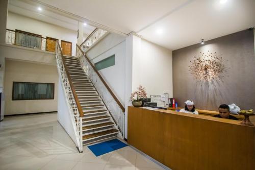 two people sitting at a counter in a room with a staircase at Kuta Suci Guesthouse in Kuta