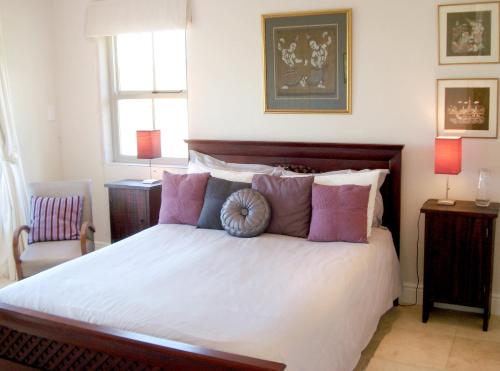 1 dormitorio con 1 cama grande con almohadas rosas y moradas en Aloe Cottage, en Darling