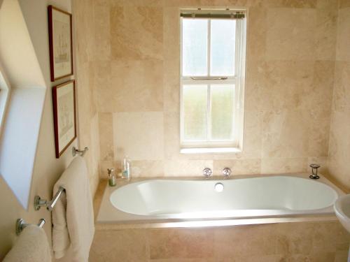une baignoire dans une salle de bain avec une fenêtre dans l'établissement Aloe Cottage, à Darling