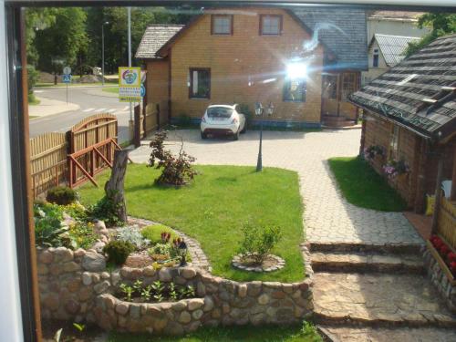 vistas a un jardín con una casa y un coche en Vila Marta, en Druskininkai