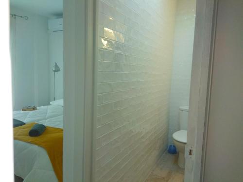 ein Schlafzimmer mit einer weißen Ziegelwand neben einem WC in der Unterkunft Abá apartamento in Almería
