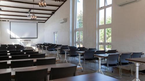a lecture room with tables and chairs and a screen at Cradle Boutique Hotel in Lanseria